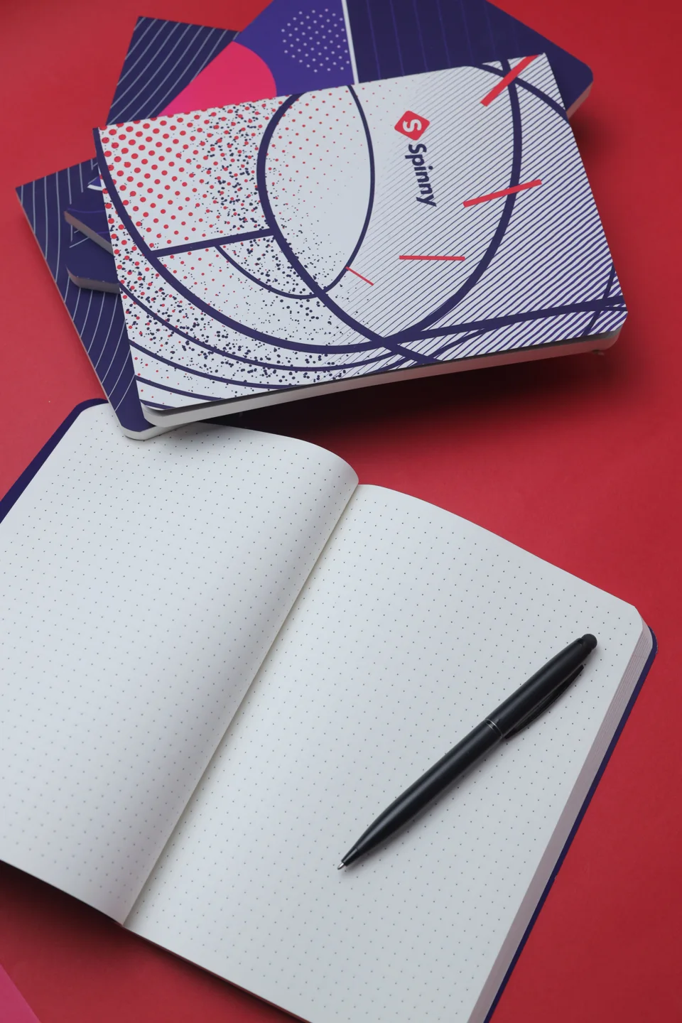 Printed graphic paper bag with blue handles beside an open notebook