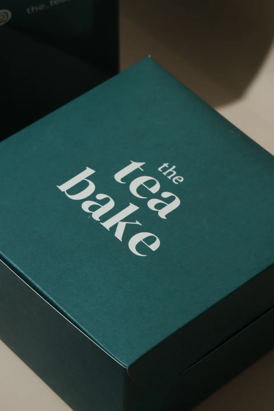 Close view of The Tea Bake logo printed on a green box lid