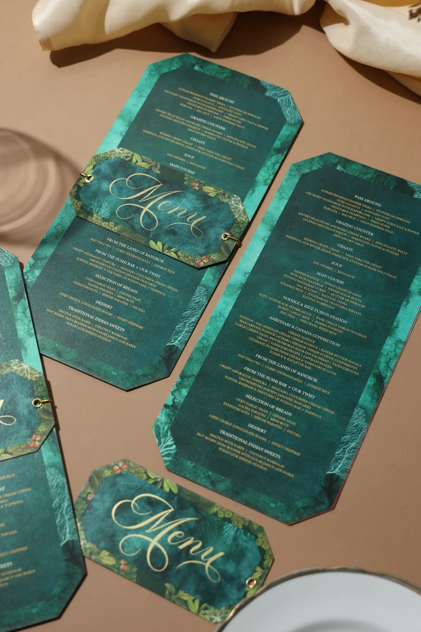 Emerald green event menus with gold typography and shaped tags