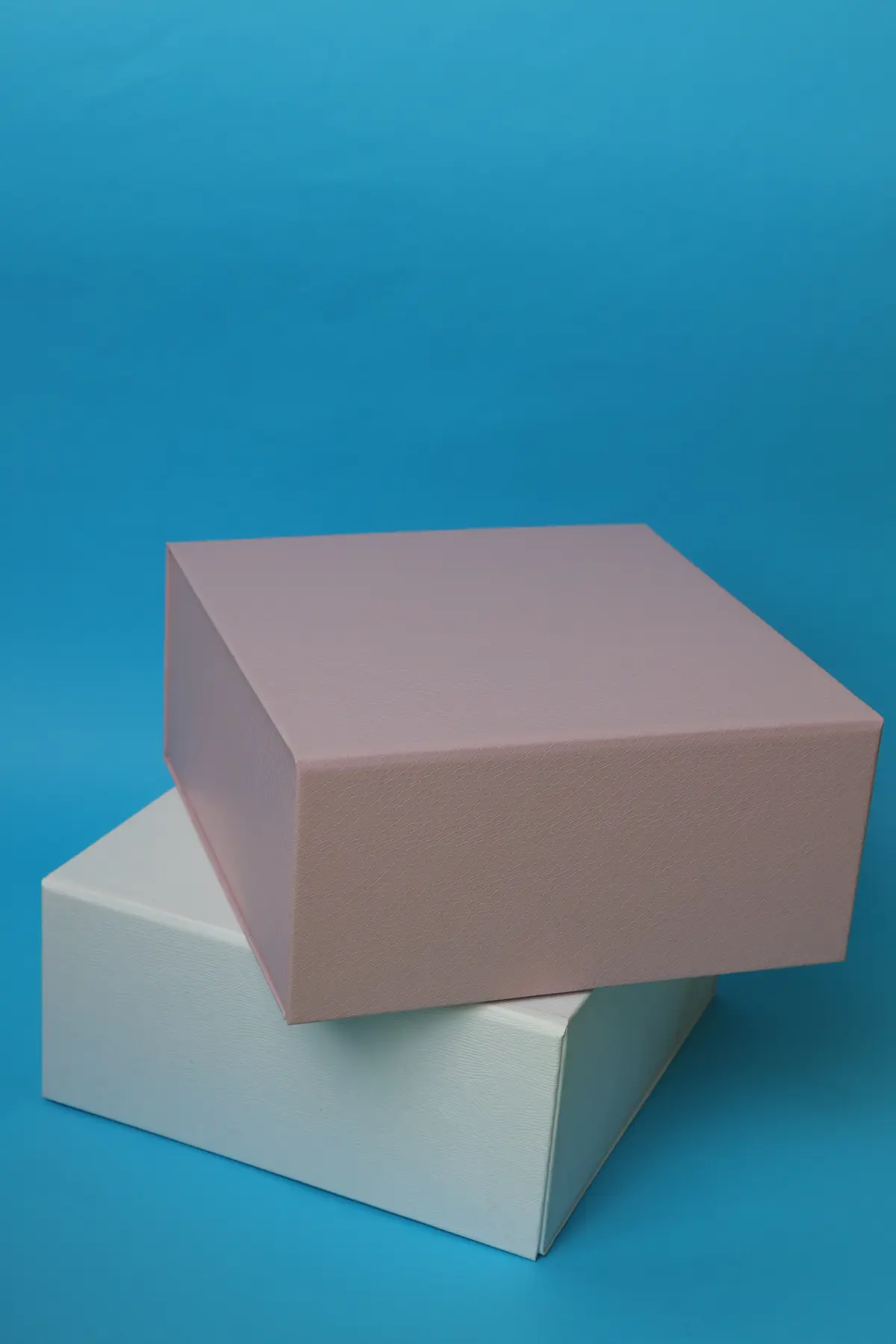 Pastel rigid gift boxes stacked against a bright blue background