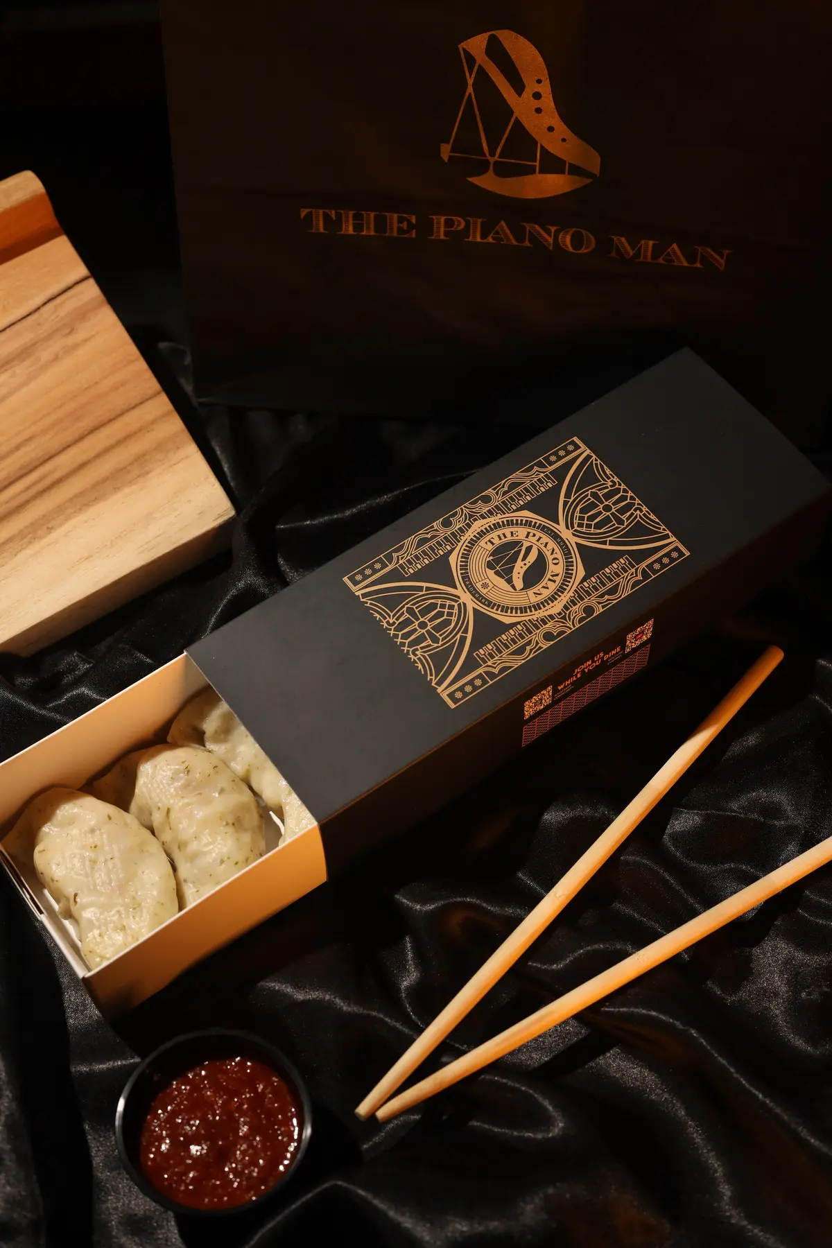 Black and gold food packaging styled on a dark dining table